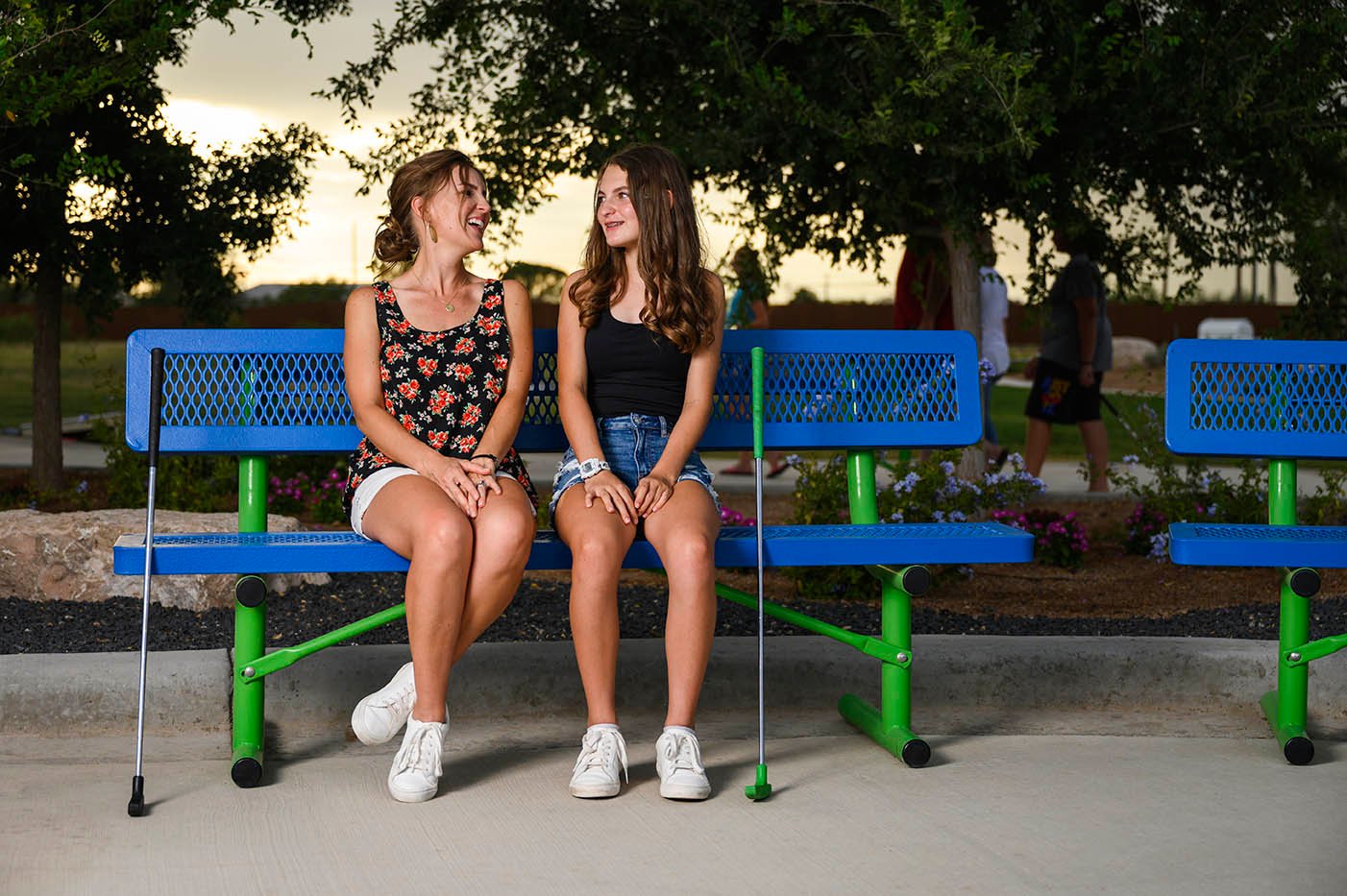 2 girls sit at a Regal Bench while playing mini golf.